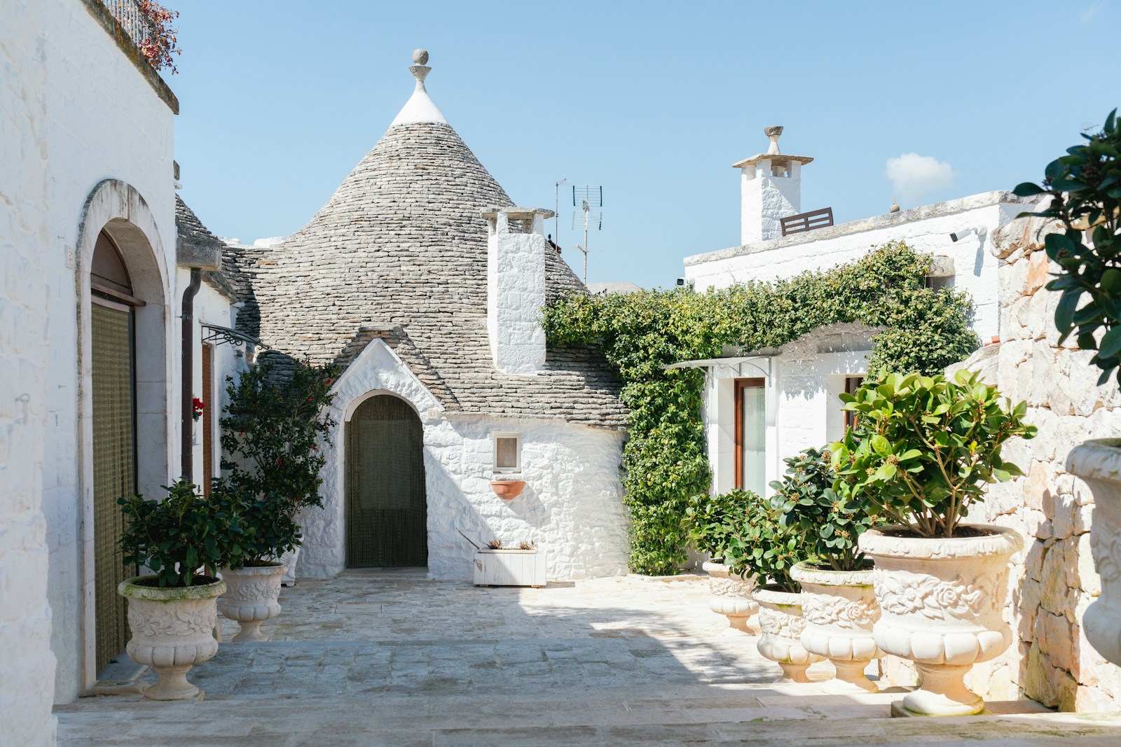 Photo by Max Böhme White trulli buildings in a sunny, italian courtyard.